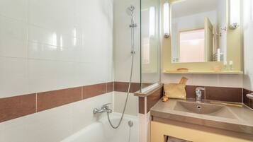 Une salle de bain équipée d’une baignoire, d’un lavabo, d’un miroir et d’un porte-serviettes.