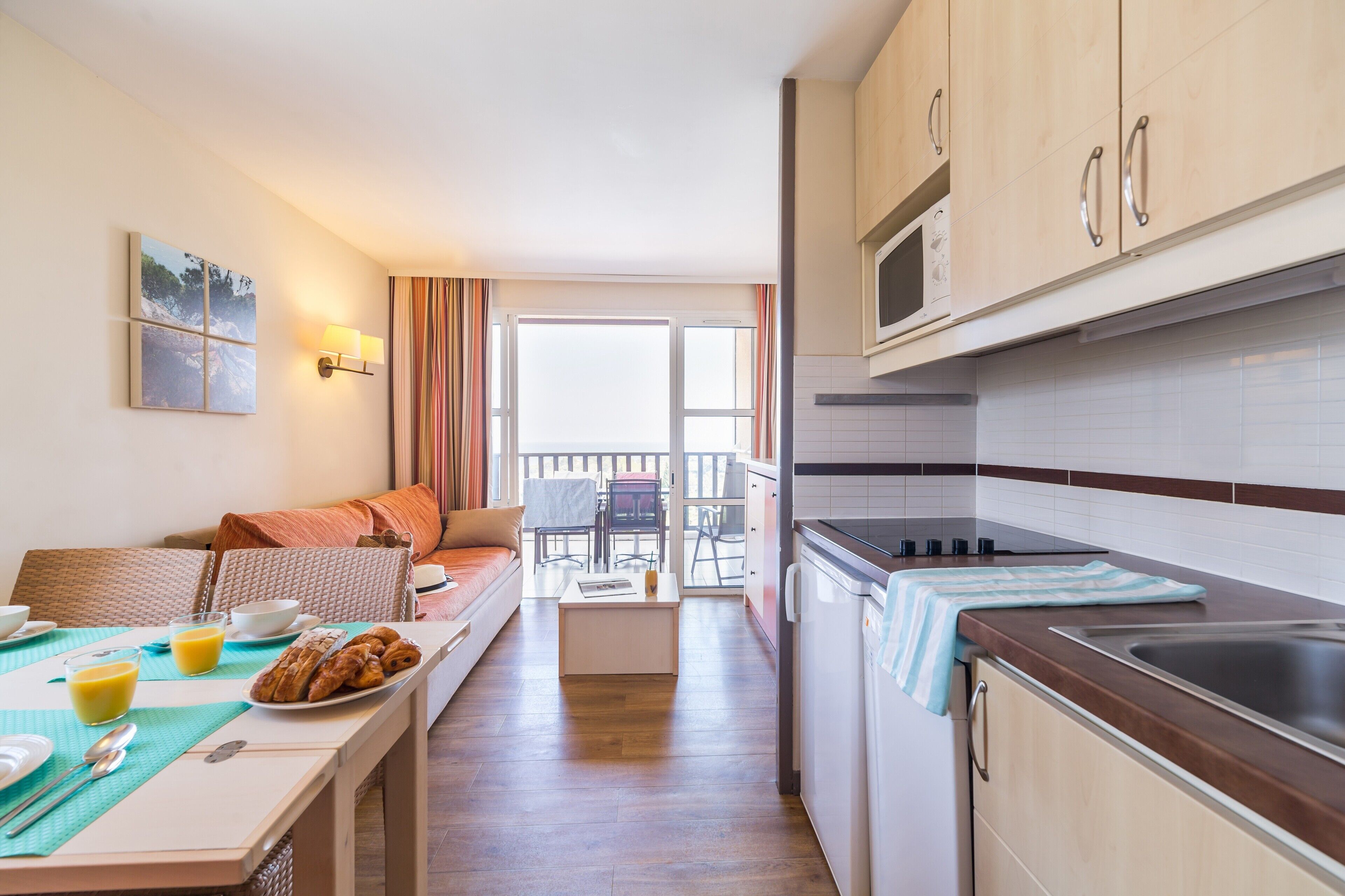 Cocina compacta con comedor, sofá y vistas al exterior.