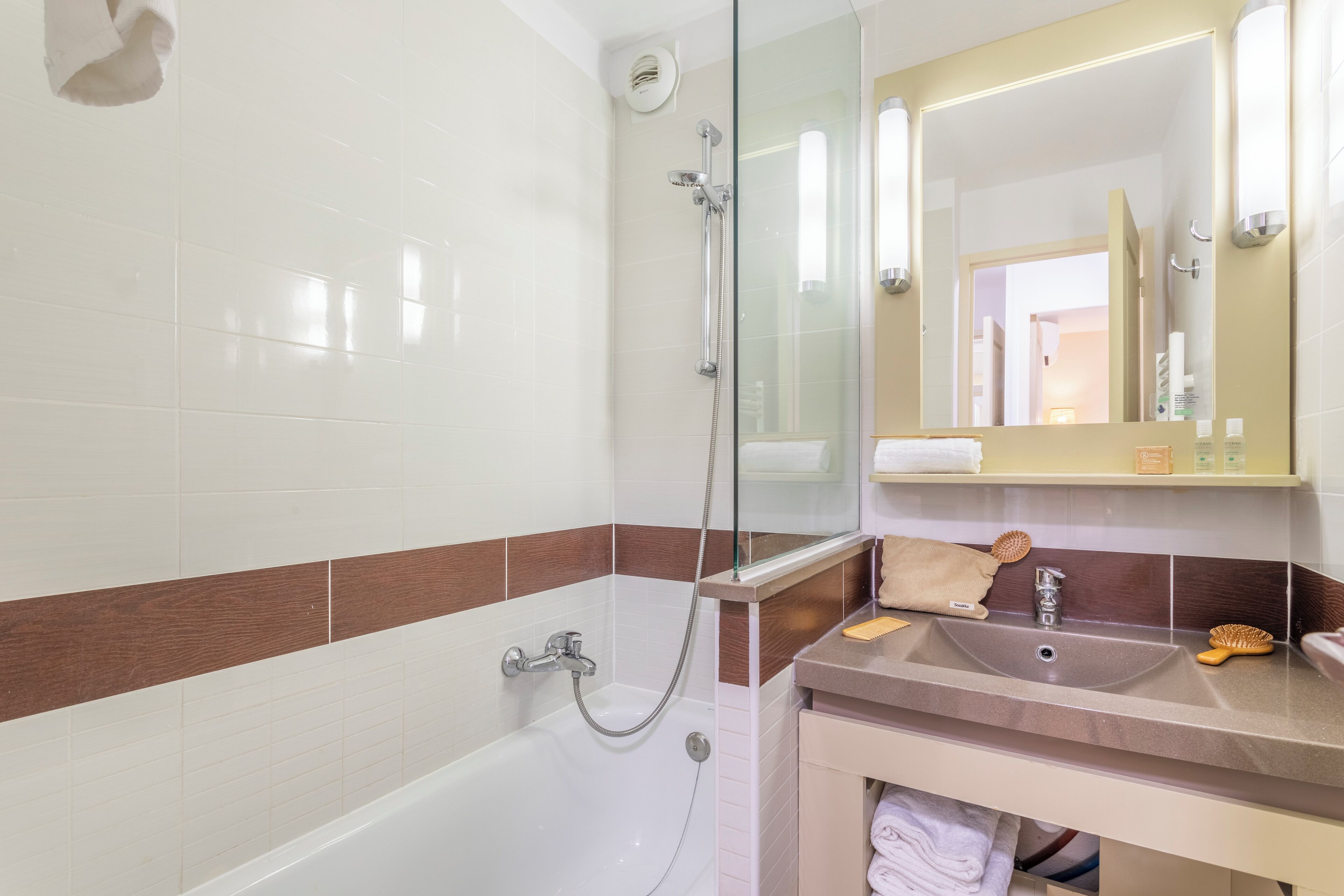 A modern bathroom with a glass shower enclosure, a vanity with a sink, and a mirror above the sink.