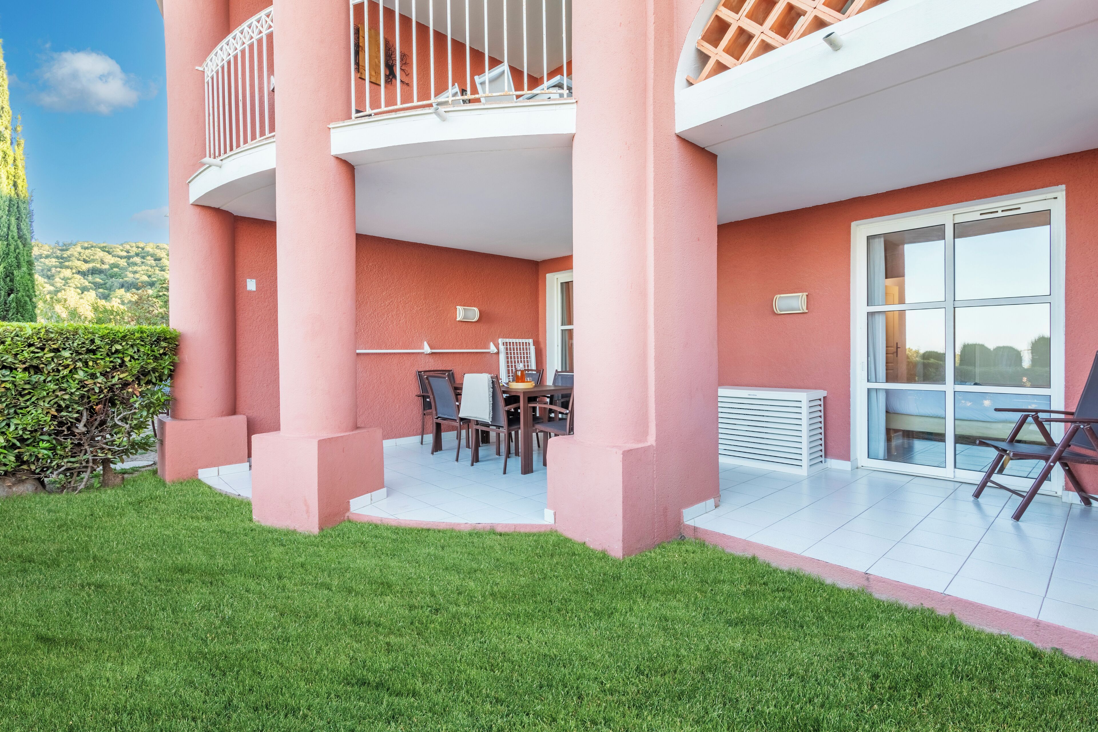Ein pinkfarbenes Gebäude mit Balkon, Tisch und Stühlen sowie einem Fenster.
