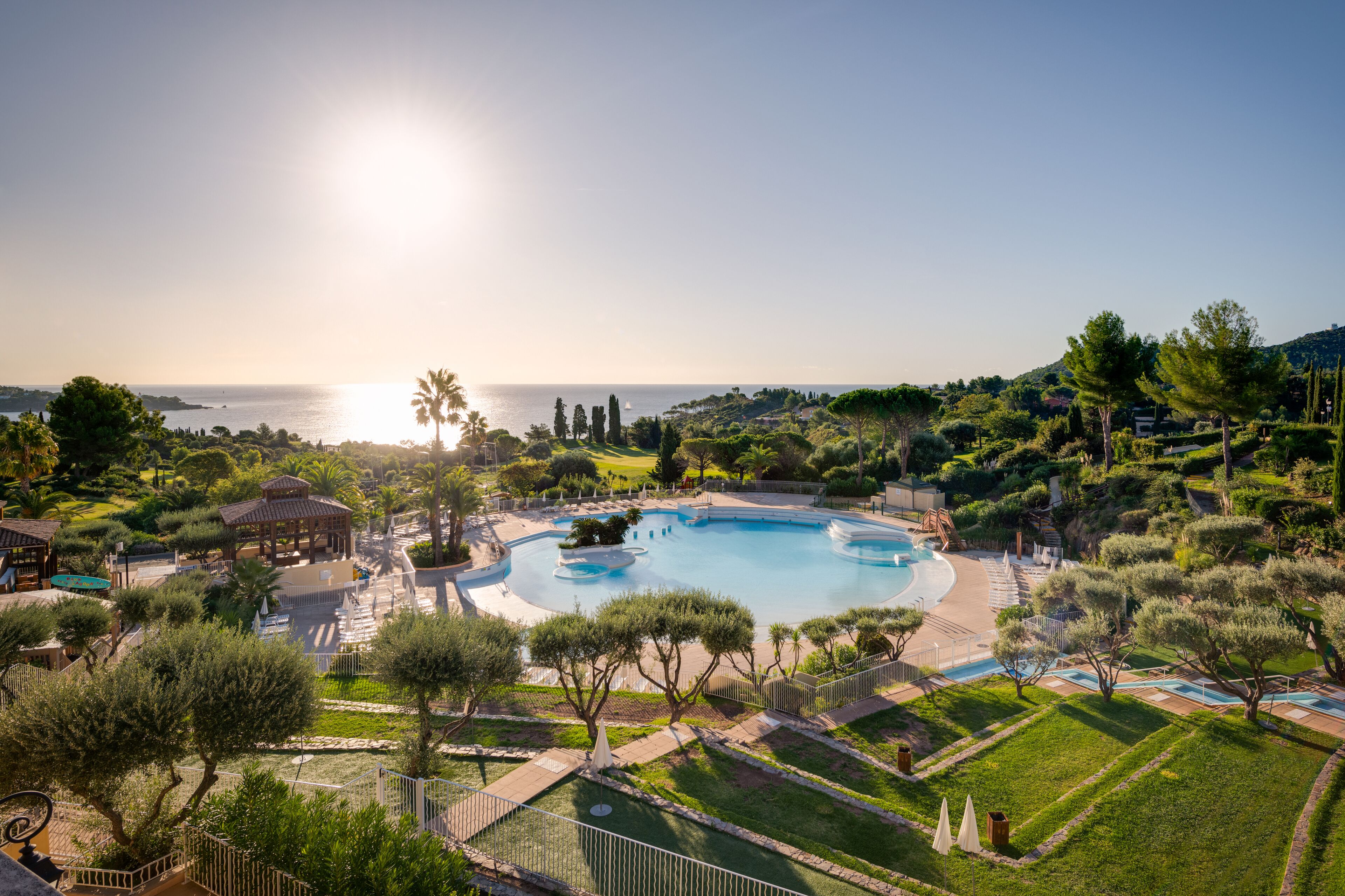 Ein Resort mit großem Schwimmbad, Palmen und Meerblick.