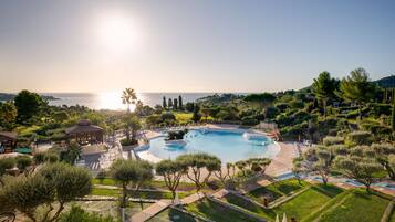 Ein Resort mit großem Schwimmbad, Palmen und Meerblick.