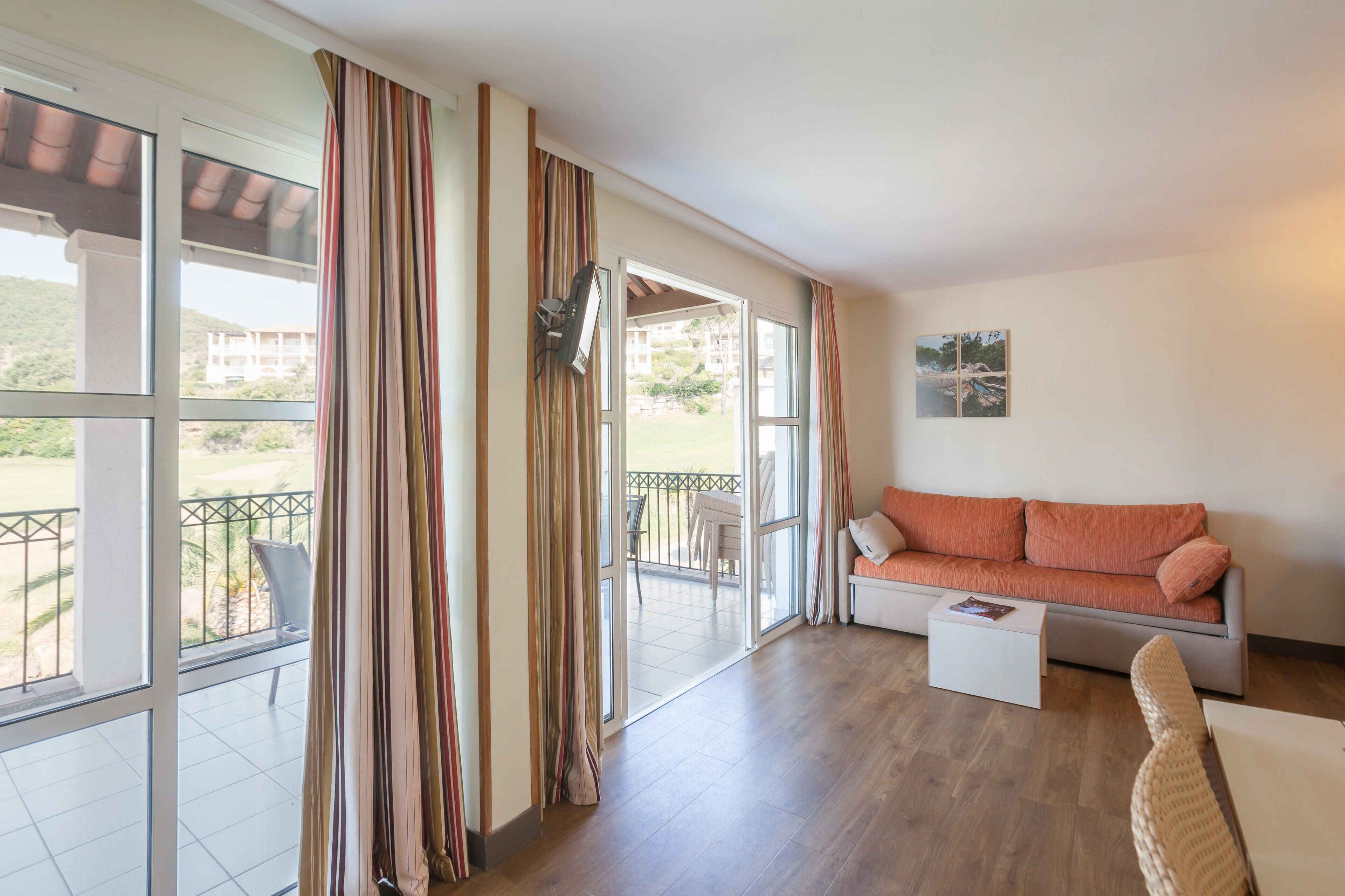 A spacious room with a balcony, a sofa, a coffee table, and a TV.