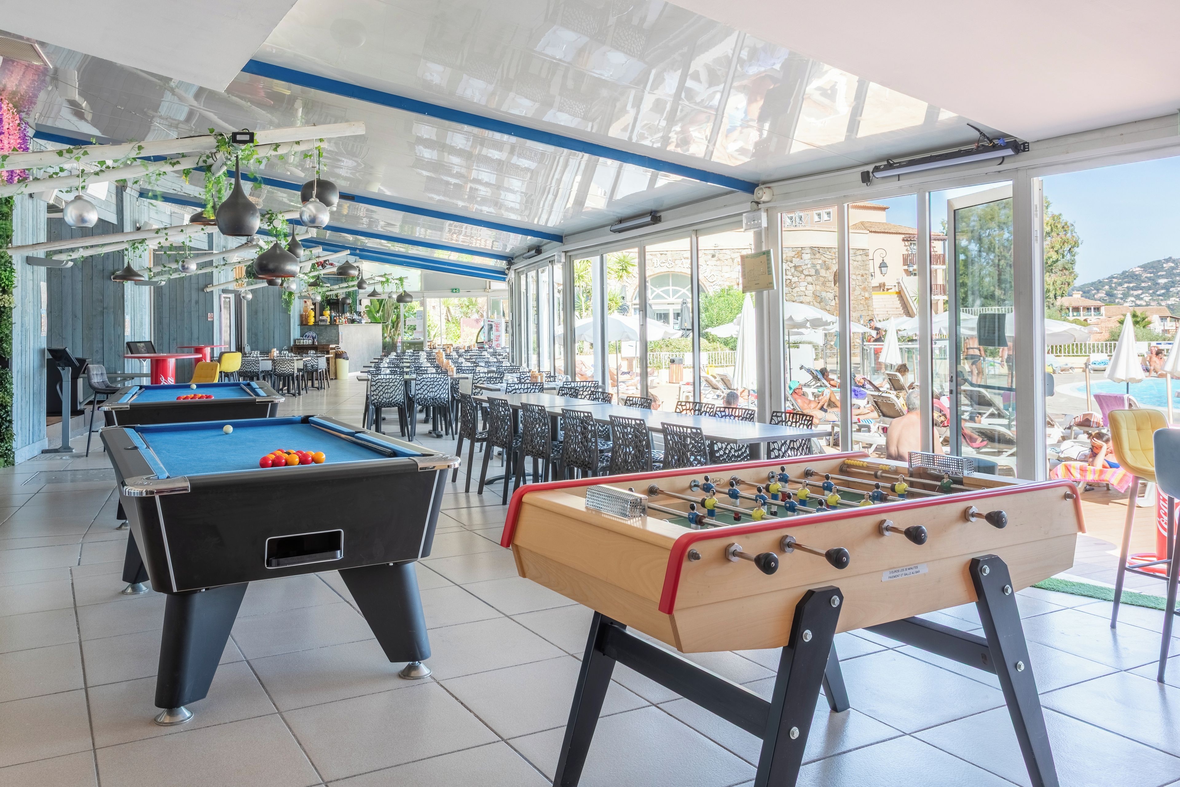 Mesa de billar, mesa de fútbol de mesa y zona de bar con vistas al exterior.