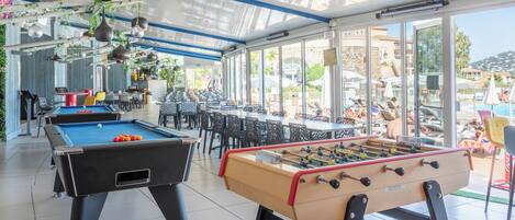 Mesa de billar, mesa de fútbol de mesa y zona de bar con vistas al exterior.
