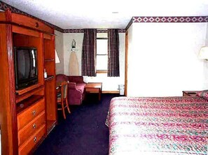 A hotel room with a bed, a desk, a chair, a dresser, and a television. - Wesley Inn & Suites (Middletown)