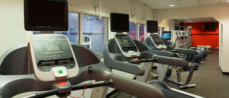 A gym with multiple treadmills, each equipped with a digital display and control panel.