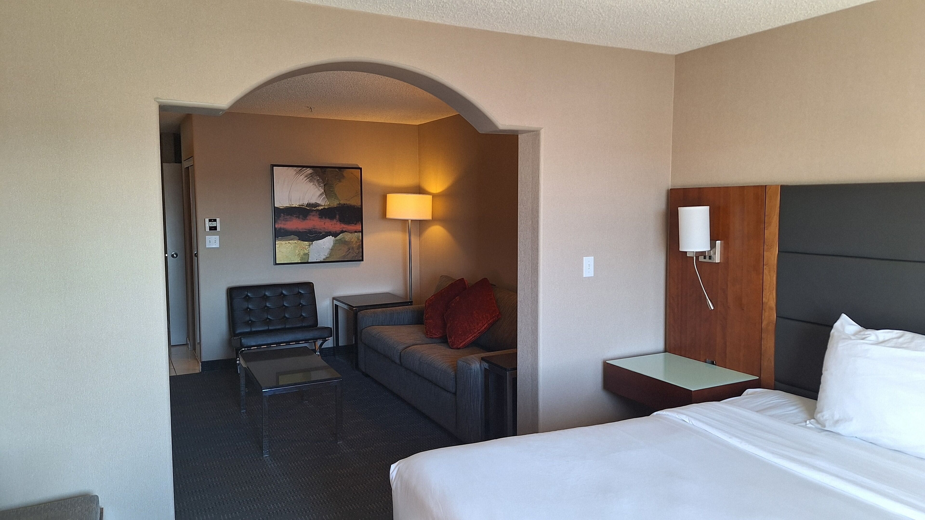Een hotelkamer met een bed, een bureau, een stoel, een bank en een schilderij aan de muur.