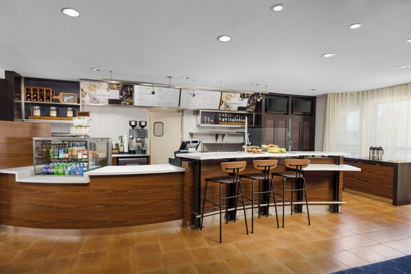 A modern bar area with a wooden counter, bar stools, and a refrigerated display.