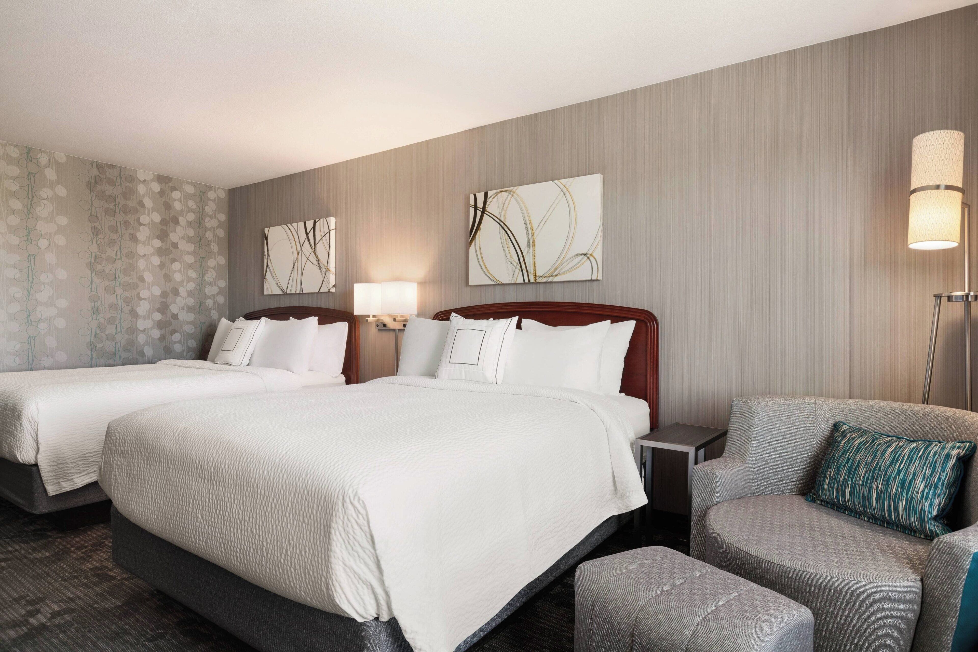 A hotel room with two beds, a sofa, and a nightstand.