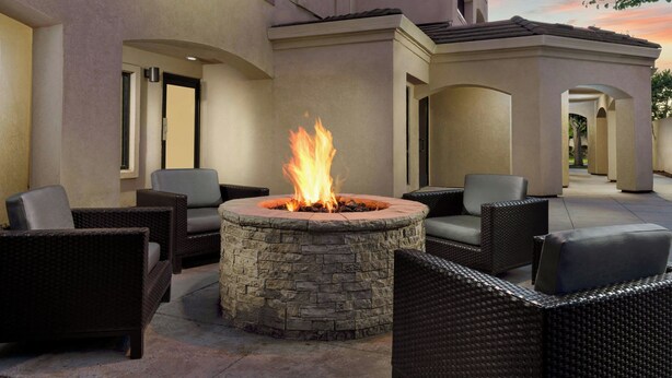 A stone fire pit surrounded by wicker furniture in an outdoor patio area.