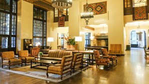 Een ruime lobby met een grote zithoek, kroonluchters en decoratieve wandpanelen.
