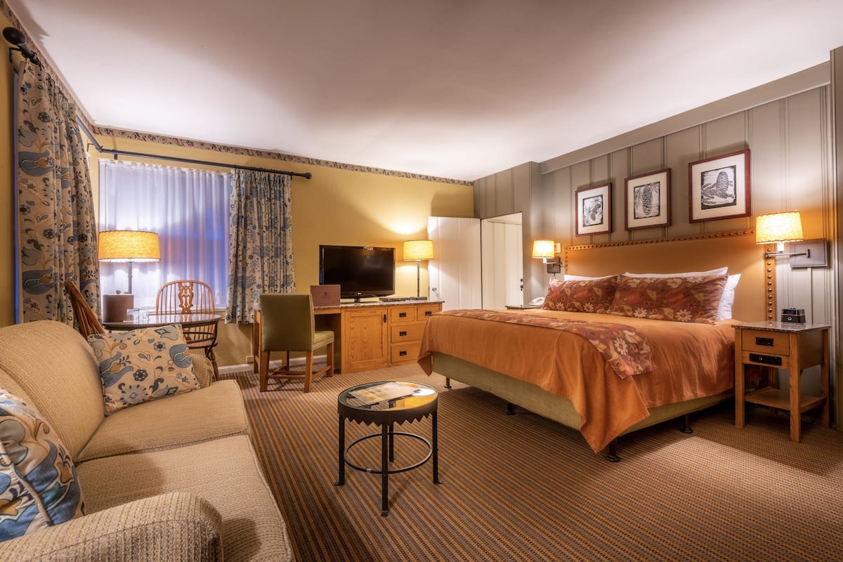Een hotelkamer met een bed, een bureau, een stoel, een televisie en een lamp.