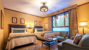 A hotel room with two beds, a sofa, a small table, and a window with curtains.