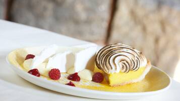Un plato de postre con merengue, crema y frambuesas.