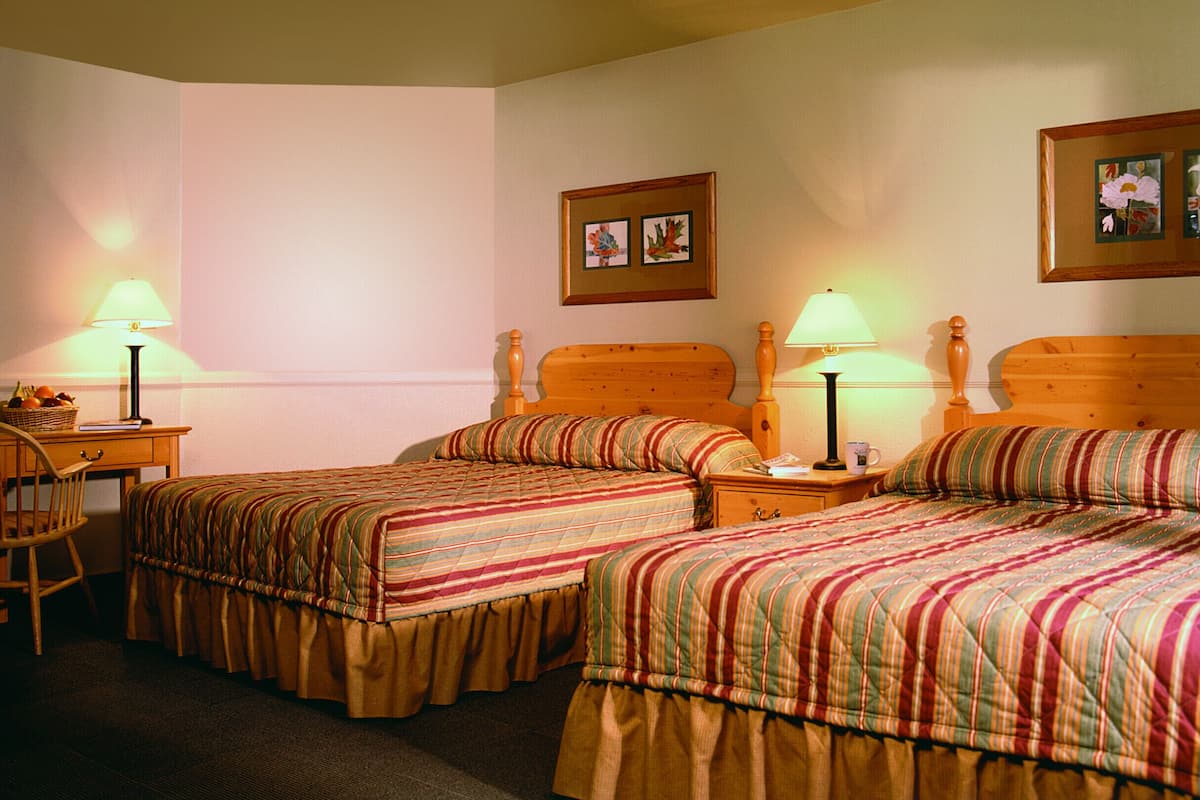 Een hotelkamer met twee eenpersoonsbedden, een bureau en twee nachtkastjes met lampen.