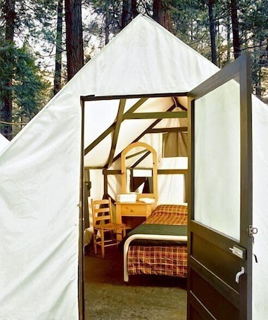 A tent with a bed, a chair, and a desk.