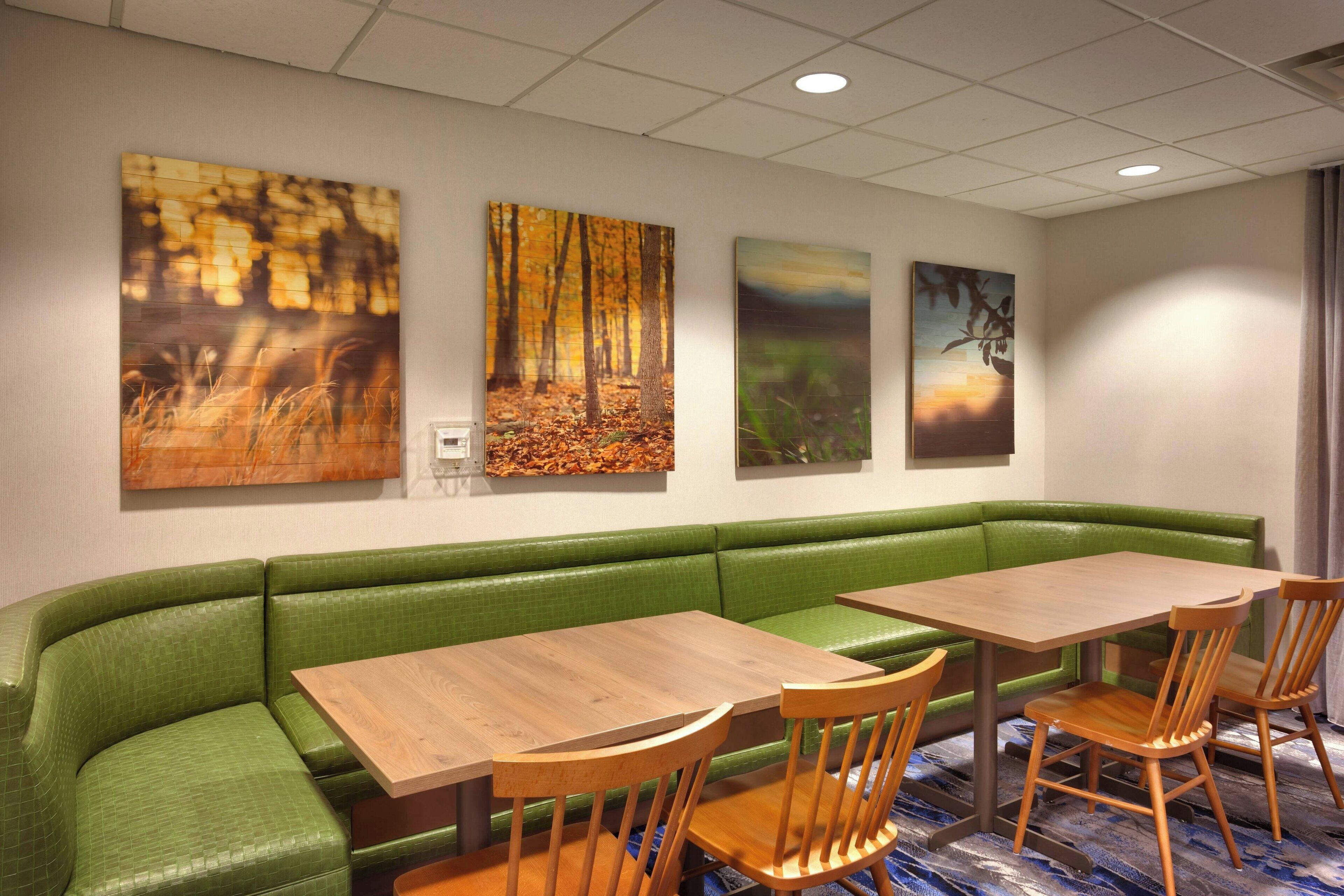 A dining area with a green booth, wooden tables, and chairs.