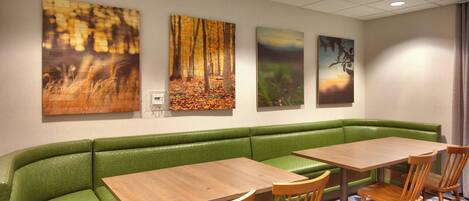 A dining area with a green booth, wooden tables, and chairs.
