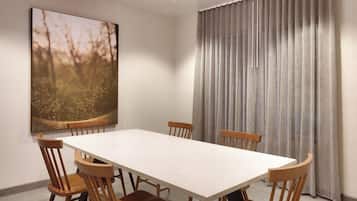 Comedor con mesa rectangular y seis sillas de madera. Un cuadro grande de un bosque adorna la pared, y una cortina gris cubre la ventana.