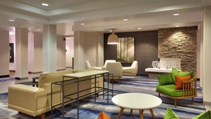 A modern hotel lobby with a beige sofa, a round white table, and a green armchair.