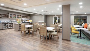 A spacious dining area with multiple tables and chairs, a kitchen area with a buffet, and a seating area with a sofa and chairs.