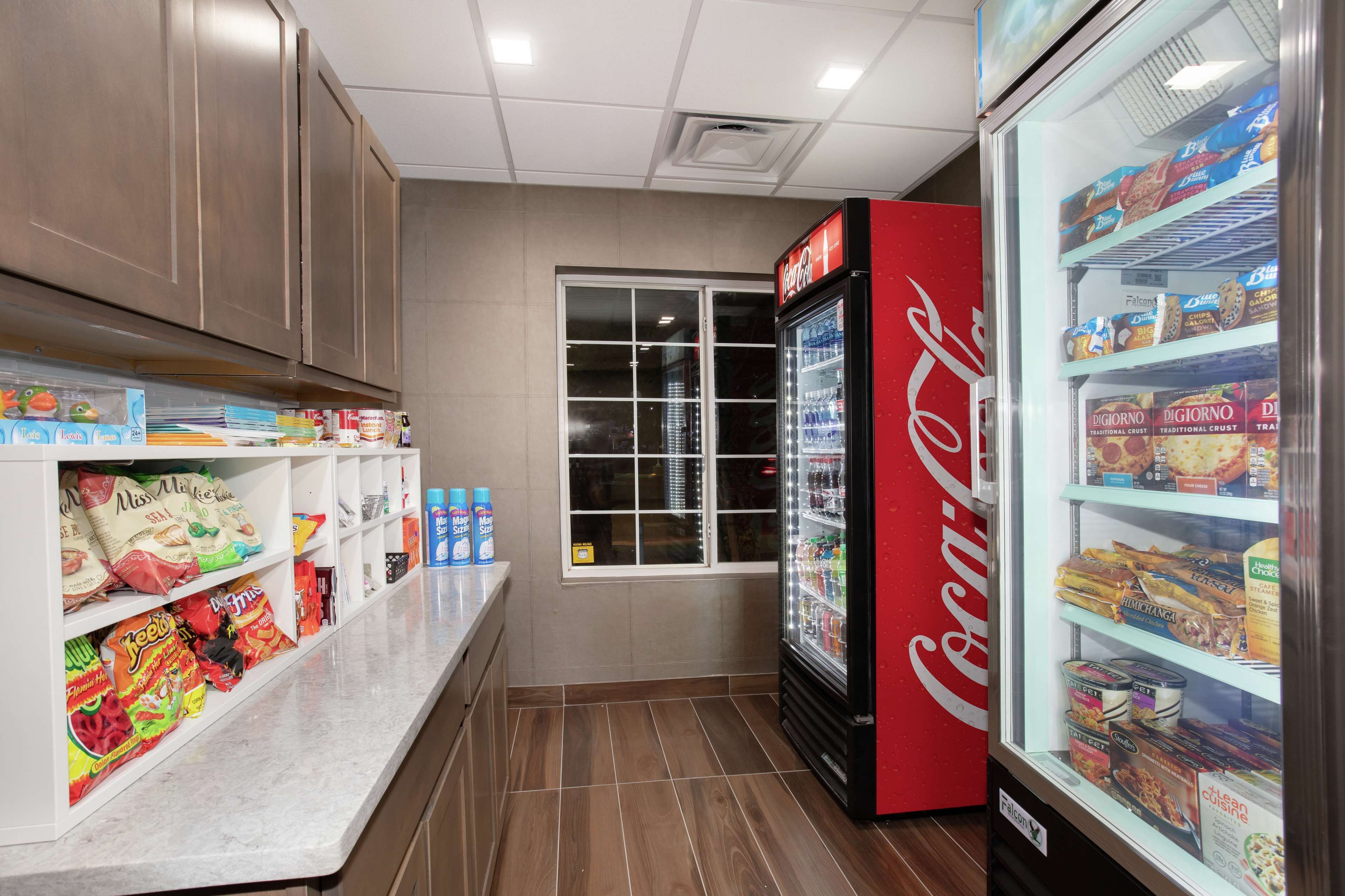 A snack bar with shelves stocked with chips, candies, and beverages, and a Coca-Cola refrigerator.
