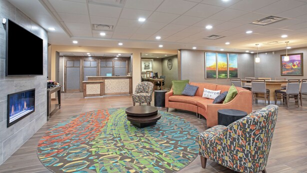A modern hotel lobby with a fireplace, comfortable seating, a large rug, and artwork on the walls.