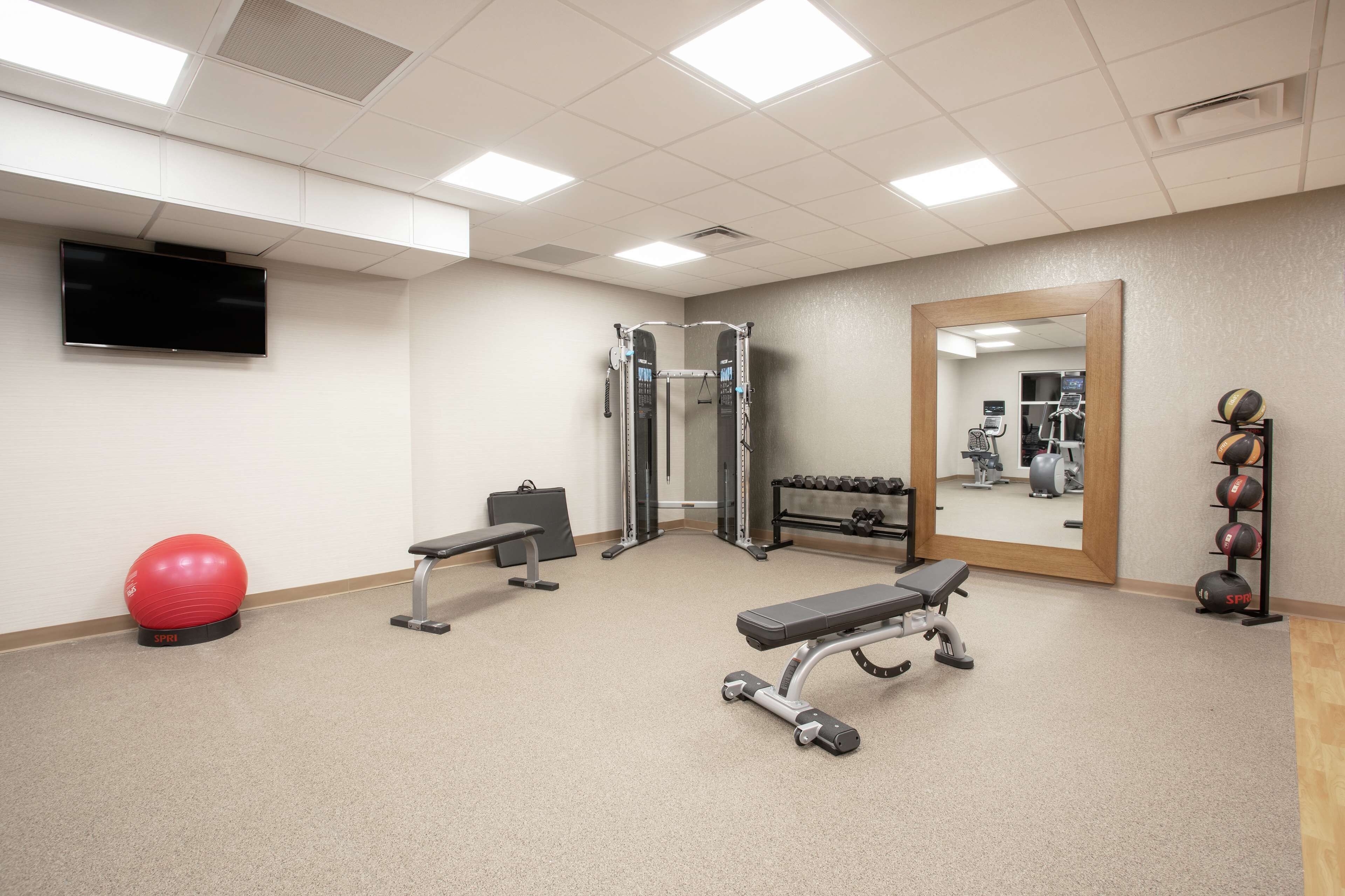A gym with exercise equipment, a TV, and a mirror.