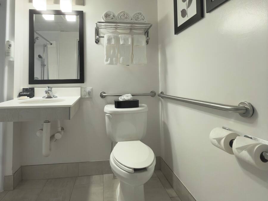 Une salle de bain moderne équipée de toilettes, d’un lavabo et de barres d’appui.