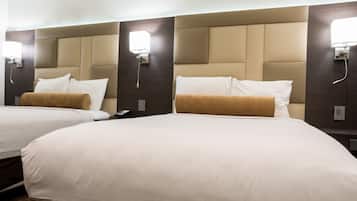 A hotel room with two beds, each with white linens and a brown throw blanket.