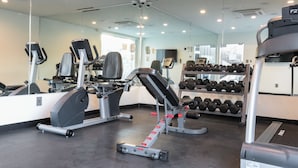 A gym with cardio machines, weight benches, and dumbbells. - Hotel Xilo Glendale (Glendale)