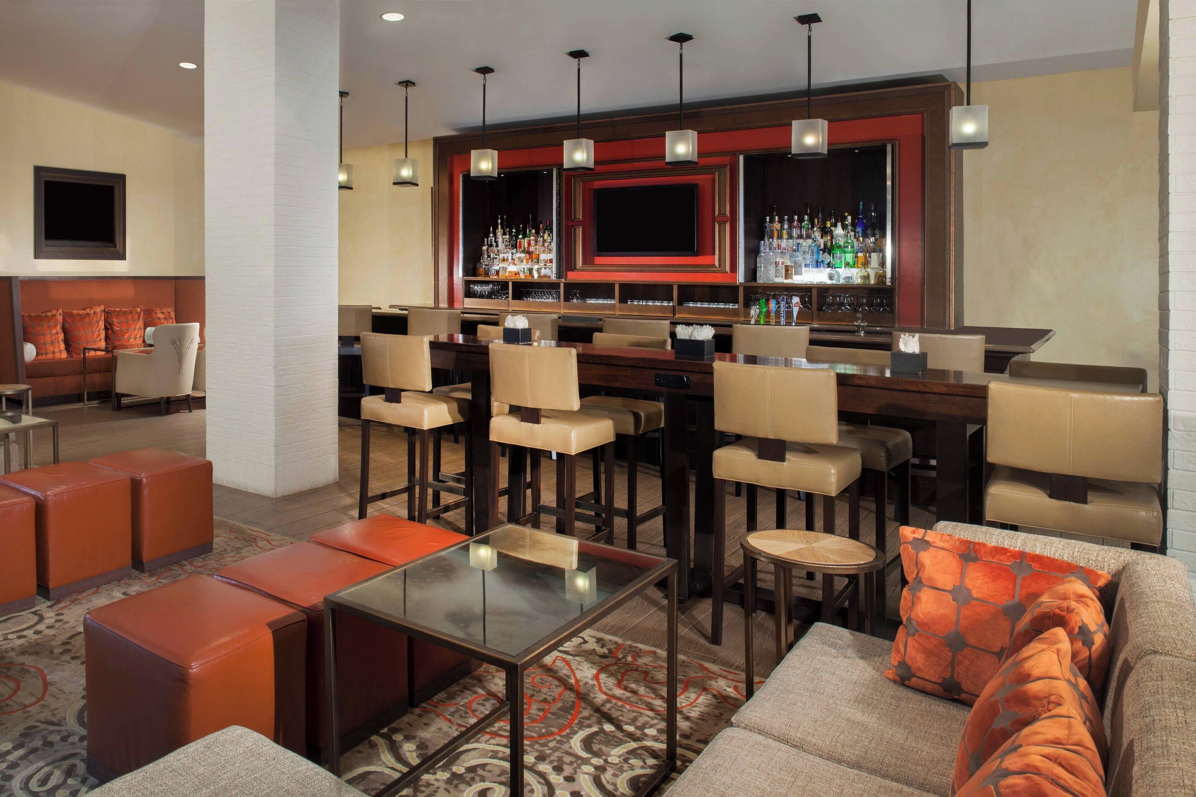 A modern bar area with leather seating, a flat-screen TV, and a well-stocked bar.