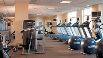 Un gimnasio con cintas de correr, elípticas y equipo de levantamiento de pesas.