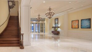 A spacious lobby with a grand staircase, elegant chandeliers, and a polished floor. - Houston Marriott Sugar Land (Sugar Land)
