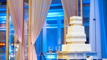 A multi-tiered wedding cake on a table with a blue tablecloth, surrounded by champagne flutes.
