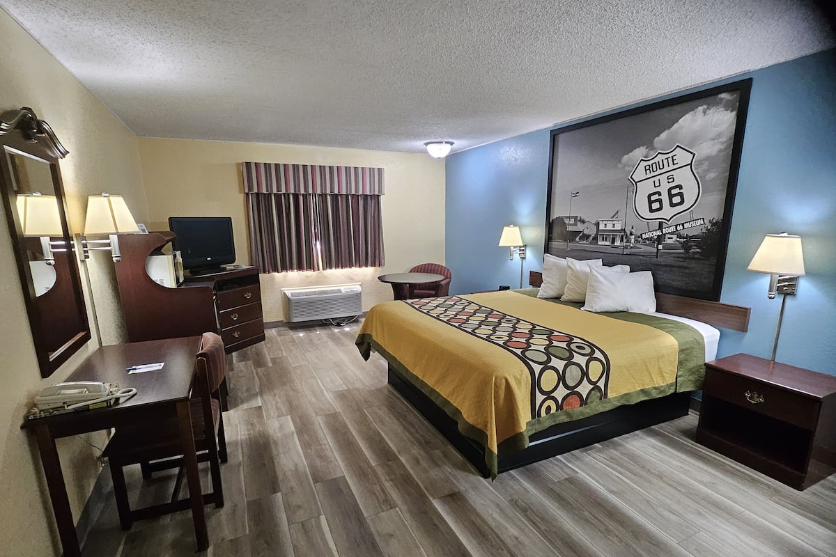 A hotel room with a bed, desk, chair, and a television.