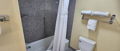 Un baño con bañera, inodoro y barra para toallas.