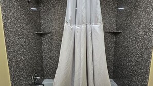 Un bagno moderno con una vasca freestanding, una tenda da doccia e pareti in granito.