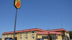 Un edificio giallo con tetto rosso e un cartello Super 8, oltre a un'antenna parabolica.