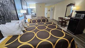 A hotel room with two beds, a desk, a chair, a microwave, and a small refrigerator.