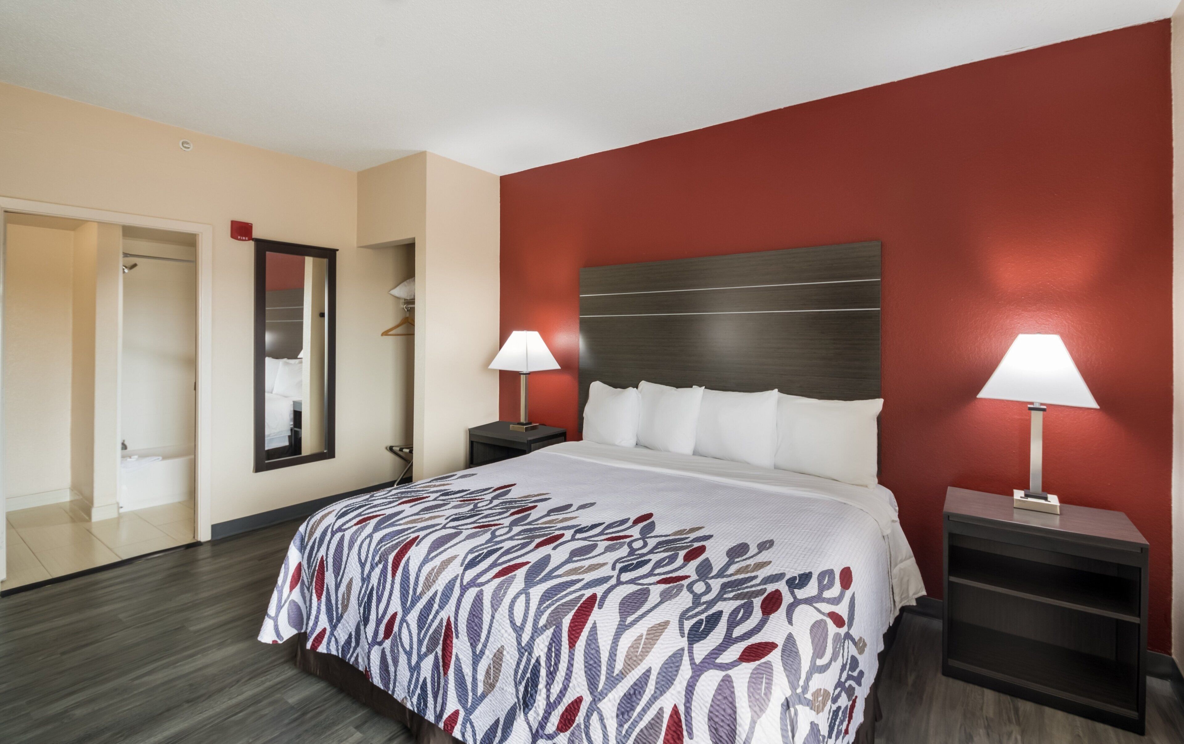 Habitación de hotel con una cama grande, dos mesitas de noche, un armario y un espejo.