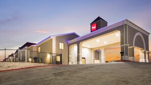 A hotel with a modern architectural design, featuring a prominent entrance with a covered area and a visible sign above the entrance. - Red Roof Inn & Suites Austin East - Manor (Manor)