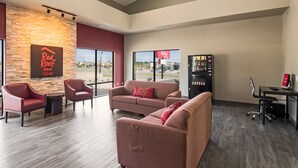 A modern interior with a seating area, a vending machine, and a Red Roof sign. - Red Roof Inn & Suites Austin East - Manor (Manor)