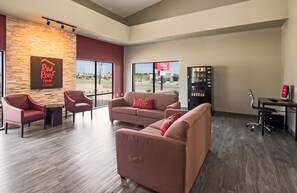 A modern interior with a seating area, a vending machine, and a Red Roof sign. - Red Roof Inn & Suites Austin East - Manor (Manor)