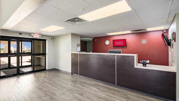 A reception area with a glass door entrance, a clock, and a sign indicating free Wi-Fi in all rooms. - Red Roof Inn & Suites Austin East - Manor (Manor)