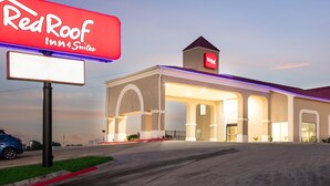 A Red Roof Inn Suites building with a prominent sign, a covered entrance, and a parking lot. - Red Roof Inn & Suites Austin East - Manor (Manor)