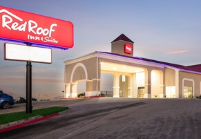 Edificio de Red Roof Inn Suites con un letrero llamativo, entrada cubierta y estacionamiento.