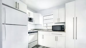 Una cocina moderna con armarios blancos, un microondas negro, una estufa y un fregadero.