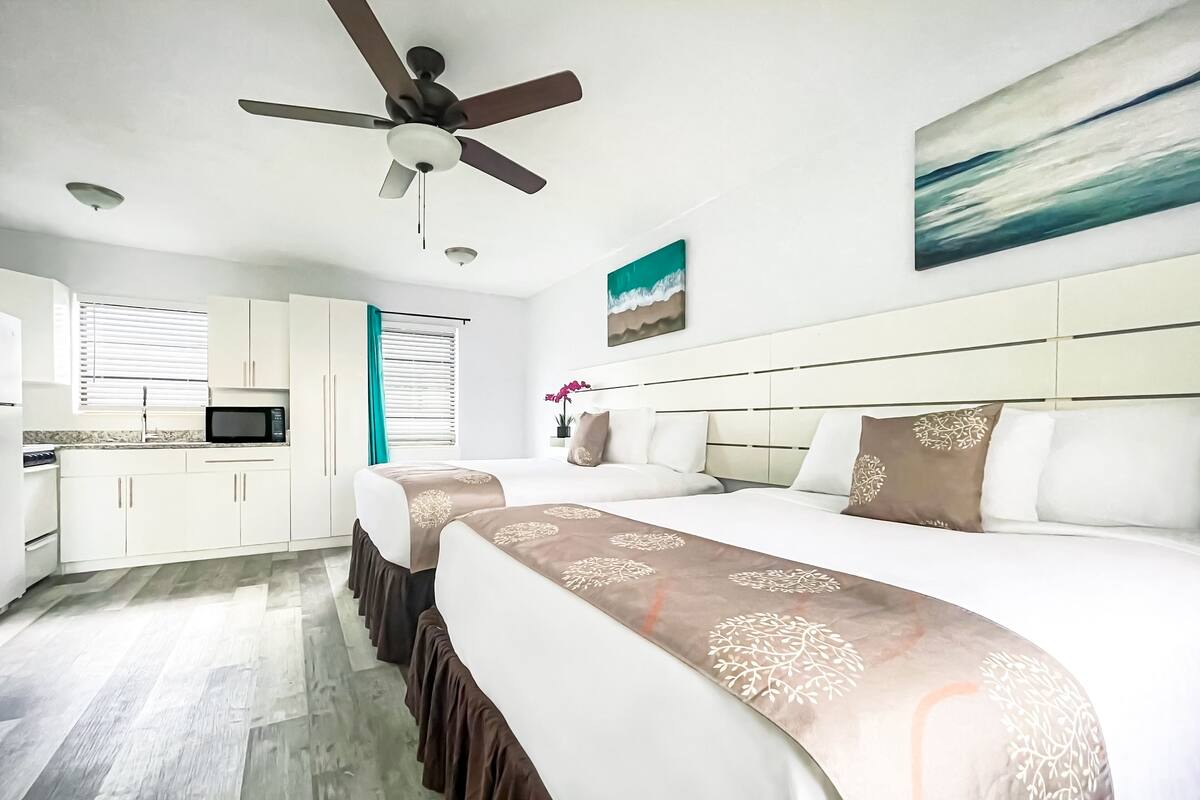A hotel room with a bed, a desk, a microwave, and a ceiling fan.